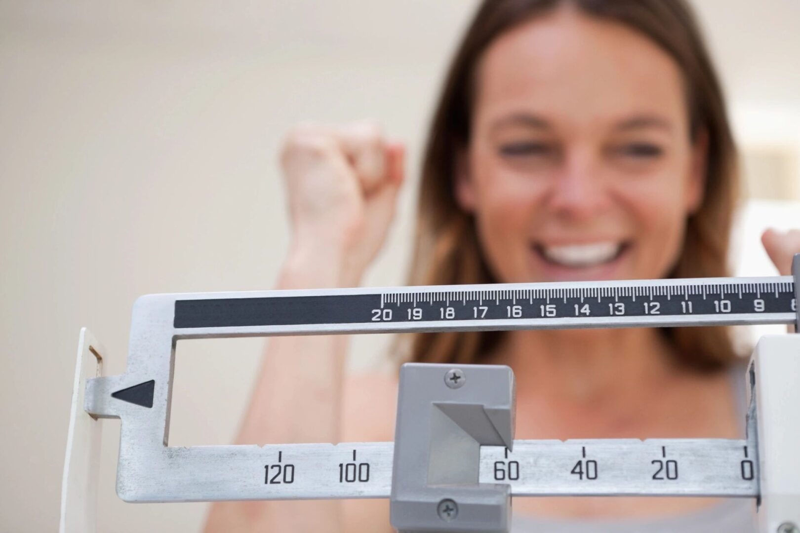 A woman is standing on the scale and smiling.